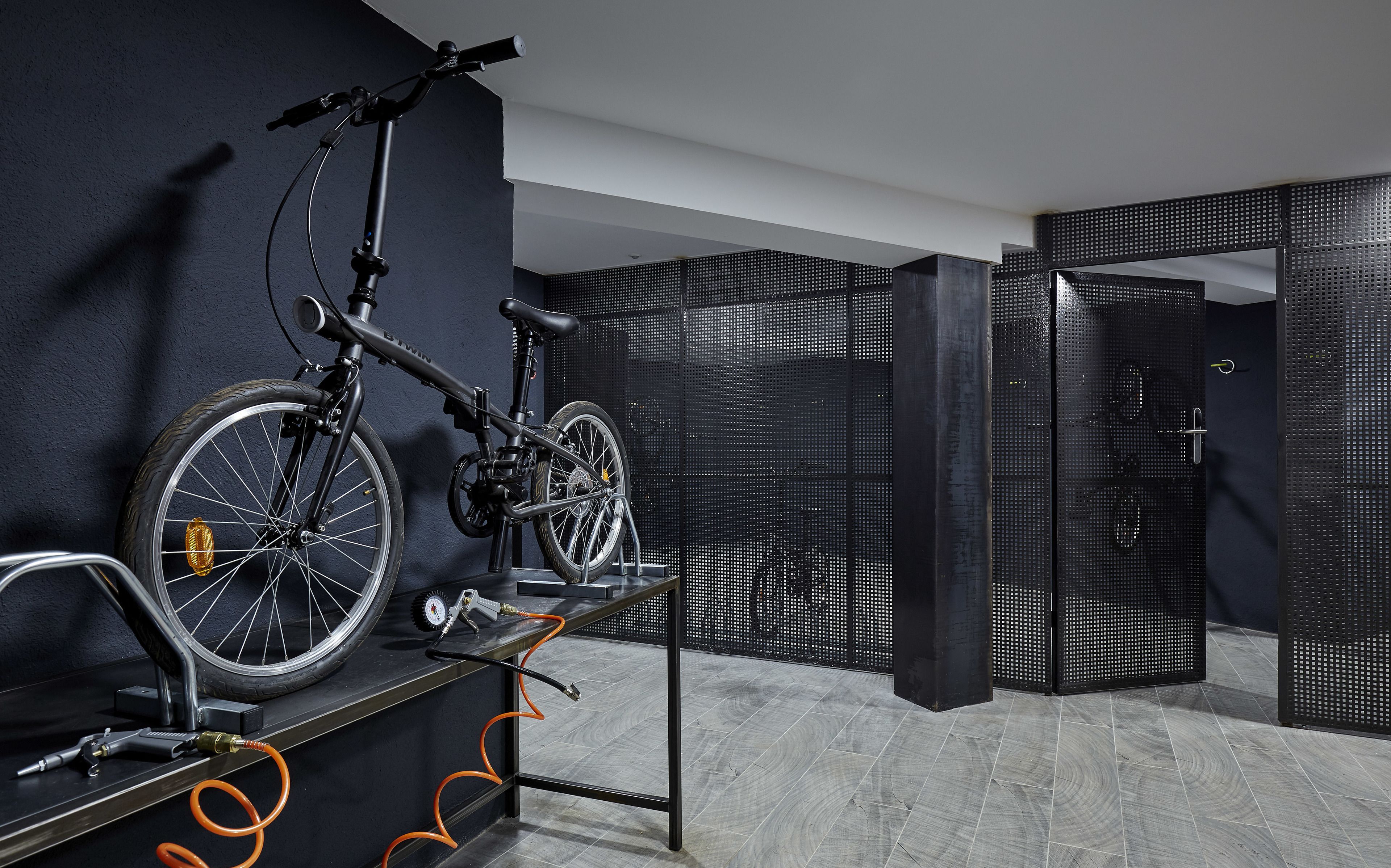 A modern room with a bicycle mounted on a stand, a water bottle, and a towel on a rack.