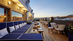 Une terrasse sur le toit aménagée avec des coins salon, des tables et des plantes en pot.