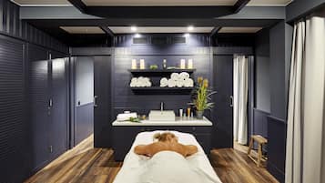 Experience relaxation in this serene space, featuring a massage table, shelf, and plush amenities.