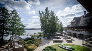 A lakeside patio with wooden gazebos, benches, and kayaks. - Porto Resort (Lilaste)