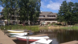 A dock with several small boats, a wooden walkway, and a building with a sloped roof in the background. - Porto Resort (Lilaste)