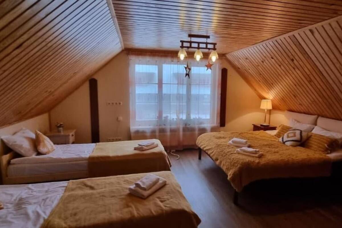 Un dormitorio abrigado en el ático con dos camas, un candelabro y una ventana con cortinas.