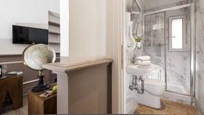 A modern bathroom with a marble shower, a sink, and a toilet. There is a globe and a small table with a book and a glass. - Côté Rome Colosseo (Rome)