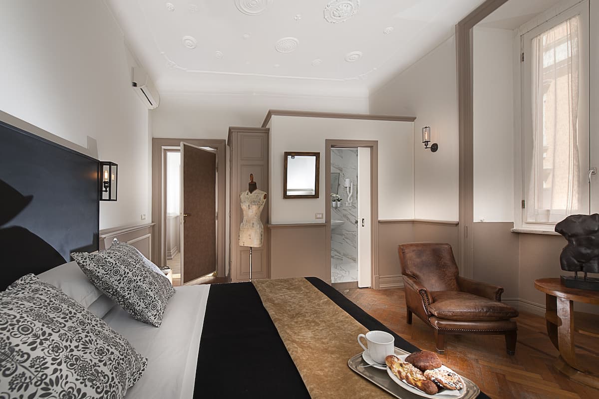 Une chambre d’hôtel avec un lit, une chaise, une table avec des pâtisseries et un miroir.
