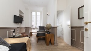 A hotel room with a bed, a desk with a globe, a television, and a window with curtains. - Côté Rome Colosseo (Rome)