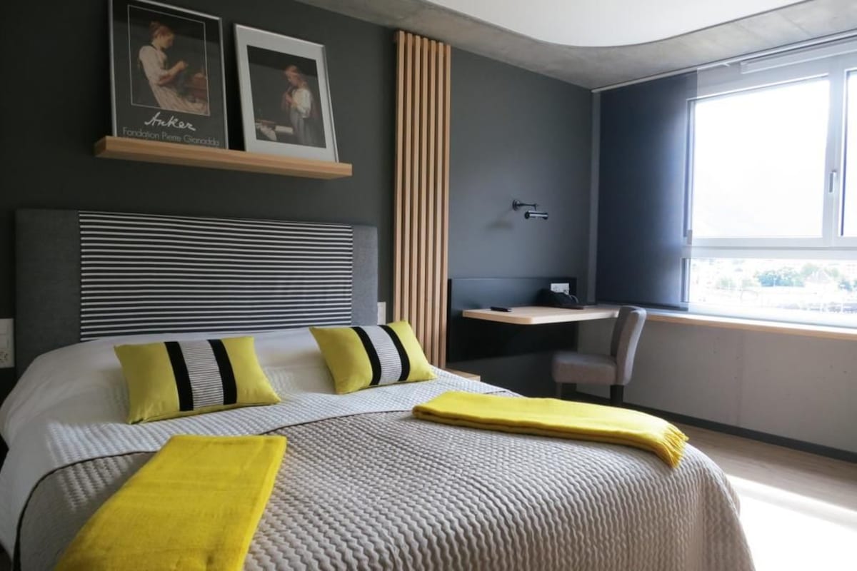Una habitación de hotel moderna con una cama grande, un escritorio y una ventana.