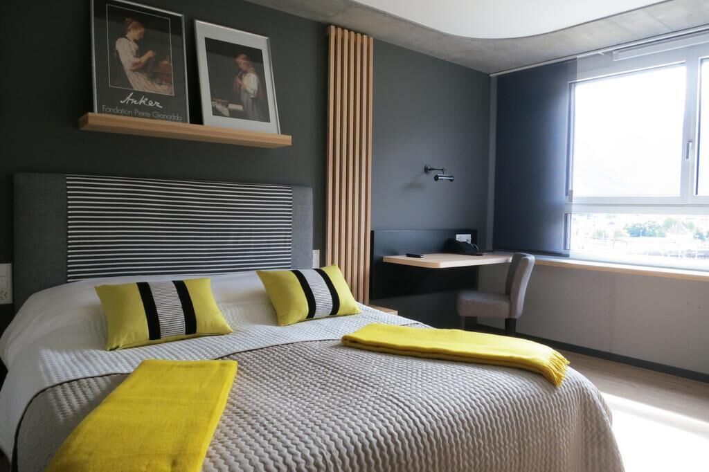 Een moderne hotelkamer met een groot bed, een bureau en een raam.