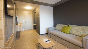 A modern living room with a sofa, a coffee table, and a television mounted on the wall.