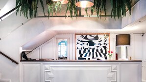 A reception desk with a modern design, a staircase to the left, and a large window with a view of the outside.