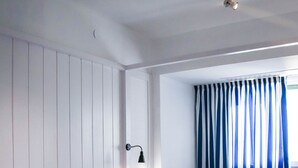 A hotel room with two beds, a tray with breakfast, a nightstand, and a window with curtains.