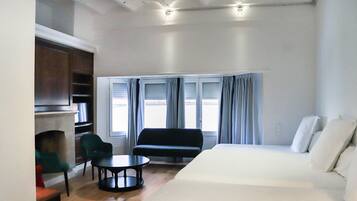 Una habitación de hotel con cama, sofá, una mesita y chimenea.