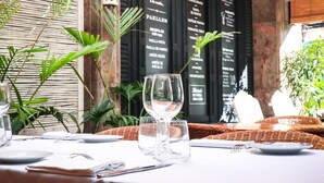 A table set with wine glasses, plates, and cutlery, with a menu board in the background.