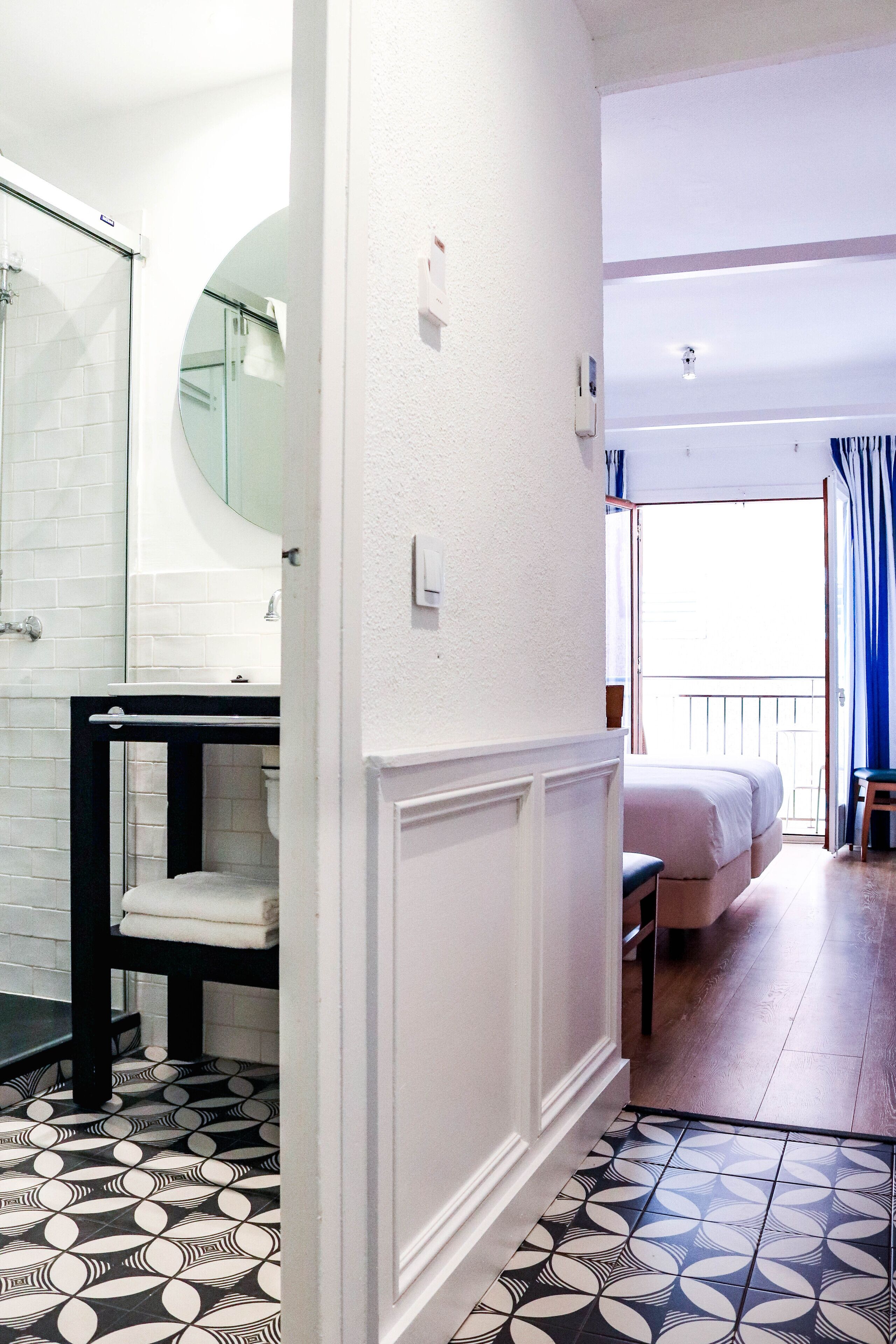 Una habitación de hotel con baño, una cama, una mesita y vistas al exterior.