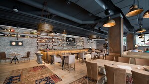 A bar area with a brick wall, shelves of bottles, and hanging pendant lights. - Wilson Palace by LOFT (Bratislava)