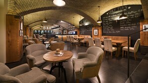 A restaurant with a brick ceiling, wooden tables, and chairs. A chalkboard menu is visible on the wall. - Wilson Palace by LOFT (Bratislava)