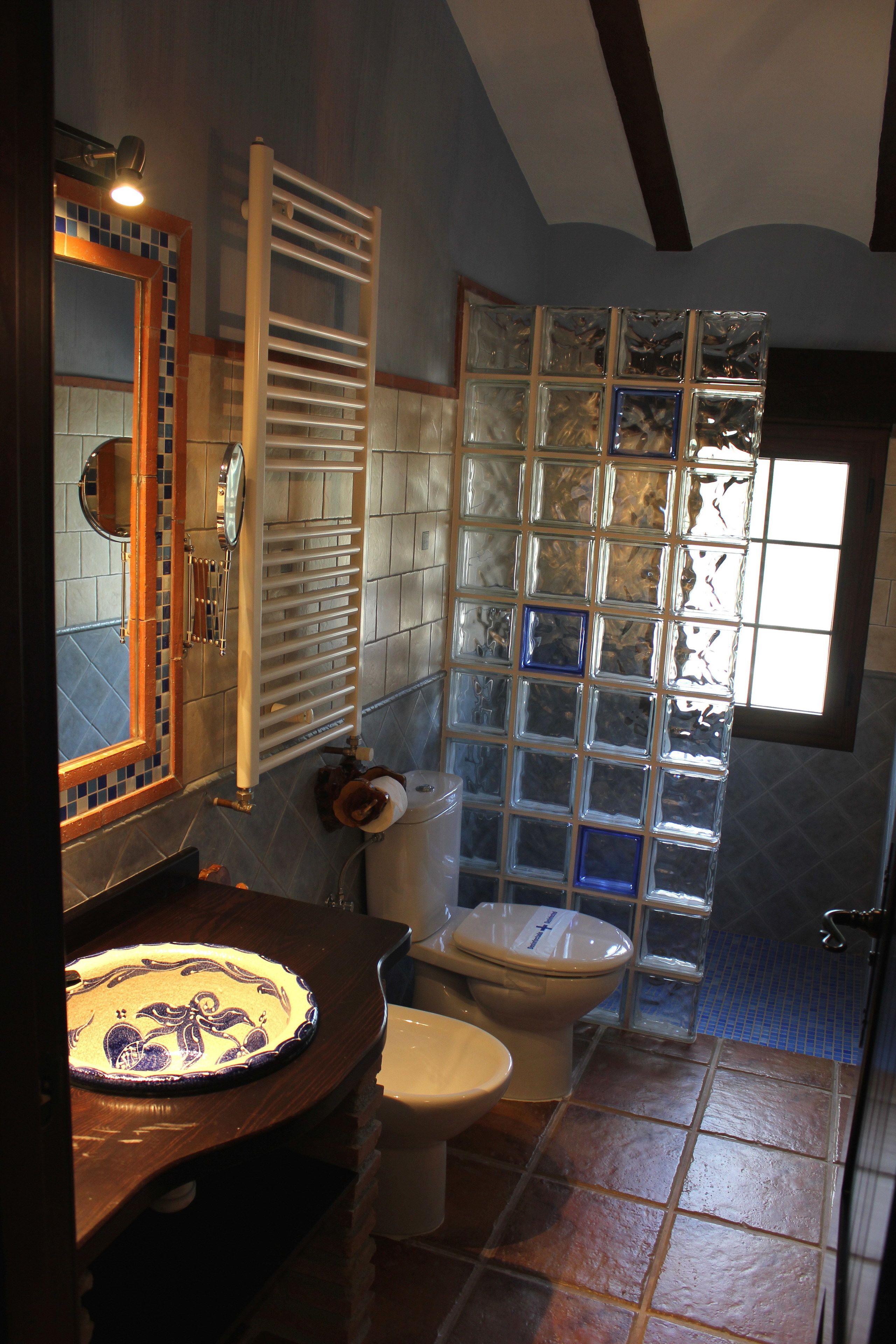 A bathroom with a wooden vanity, a toilet, and a glass shower enclosure.