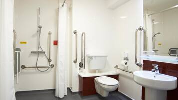 A bathroom with a toilet, sink, shower, and grab bars.