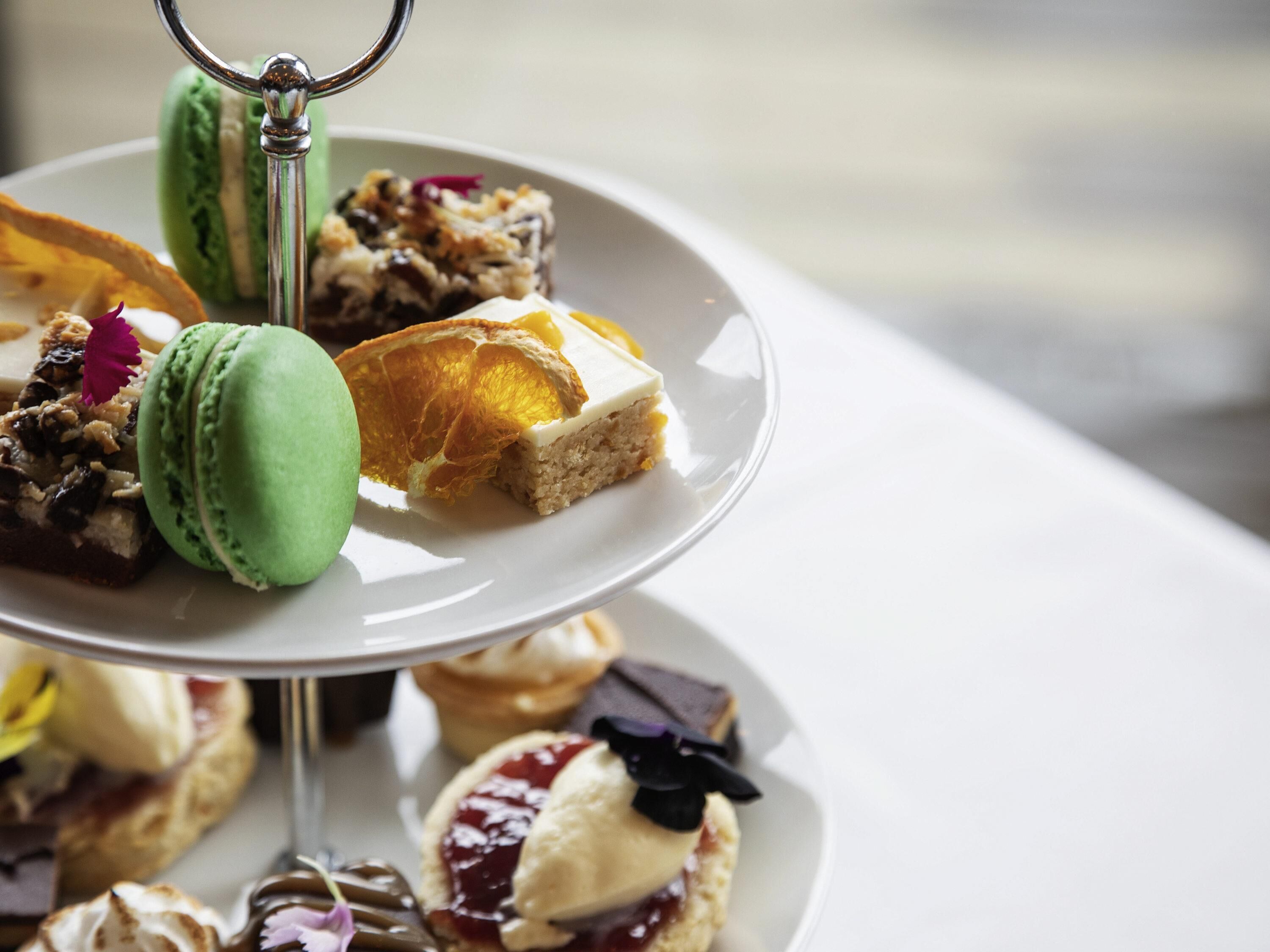 A multi-tiered dessert stand with various pastries and a green macaron.