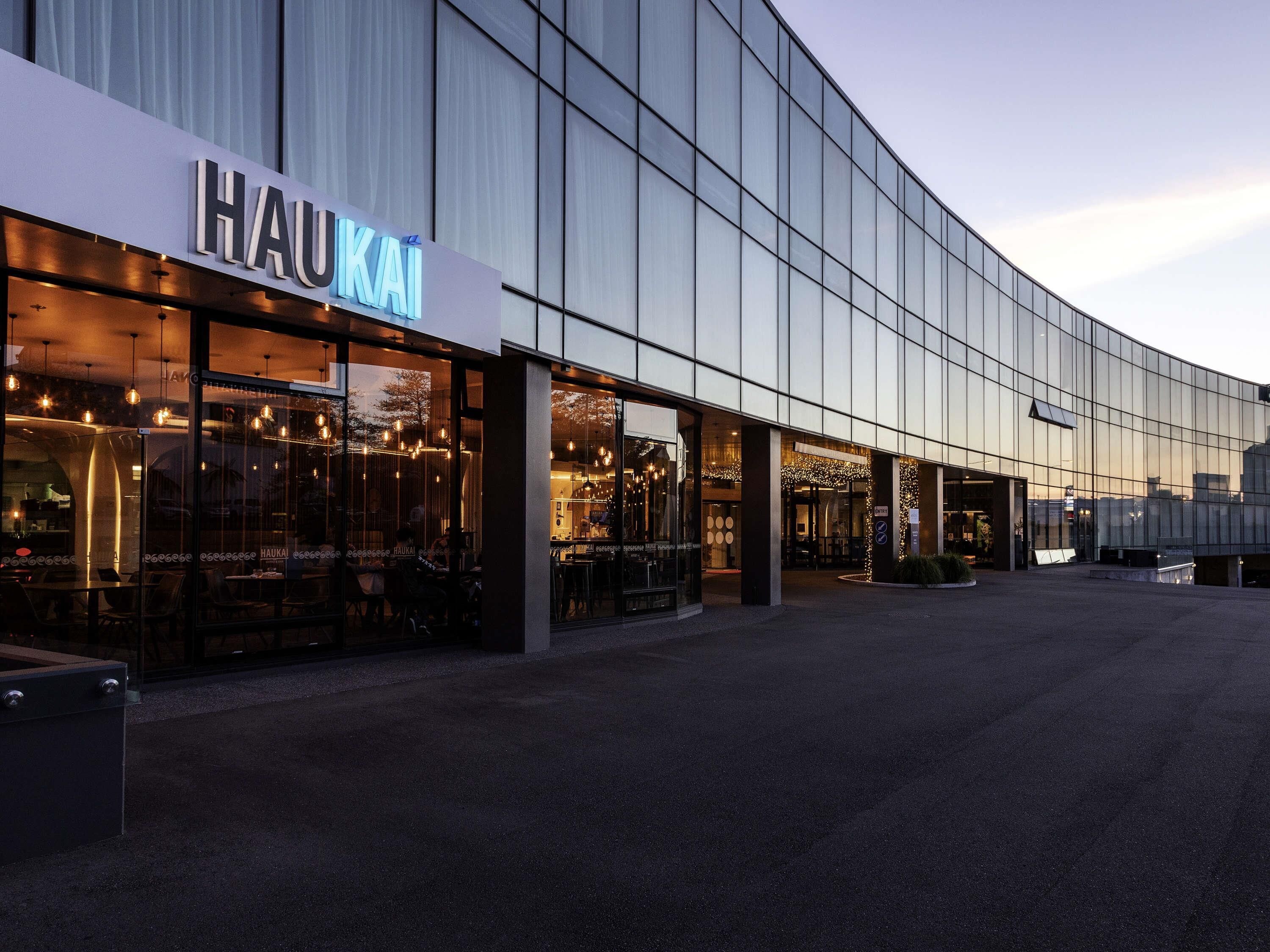 A modern building with a glass facade and a sign reading 'HAUKAI'.