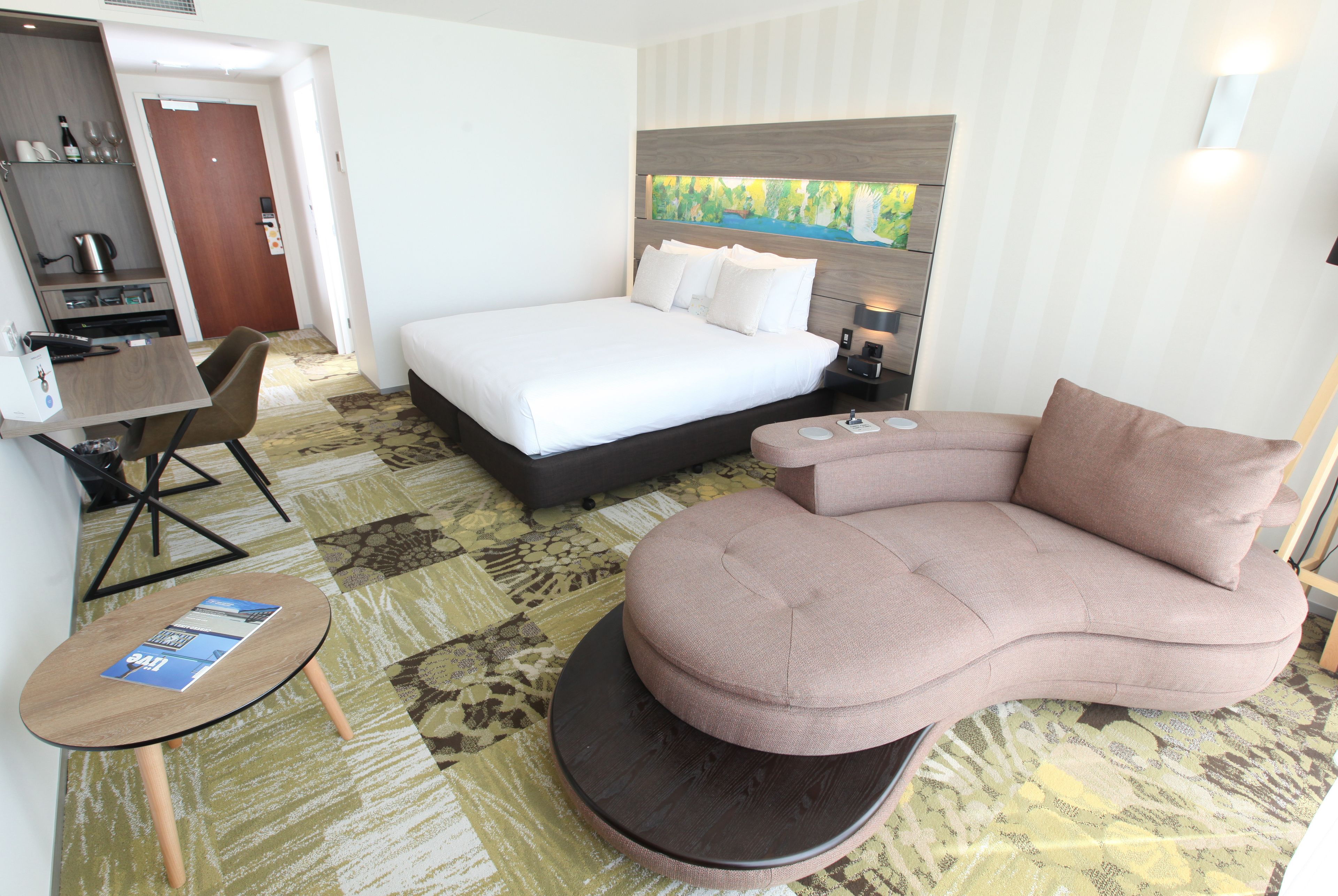 Ein Hotelzimmer mit Bett, Sofa, kleinem Tisch und Schreibtisch.