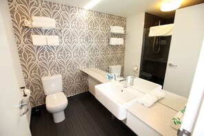 A modern bathroom with a toilet, bidet, sink, and mirror. - Novotel New Plymouth Taranaki (New Plymouth)