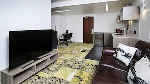 Una sala de estar moderna con un televisor de pantalla plana, un sofá de cuero marrón y una alfombra estampada.