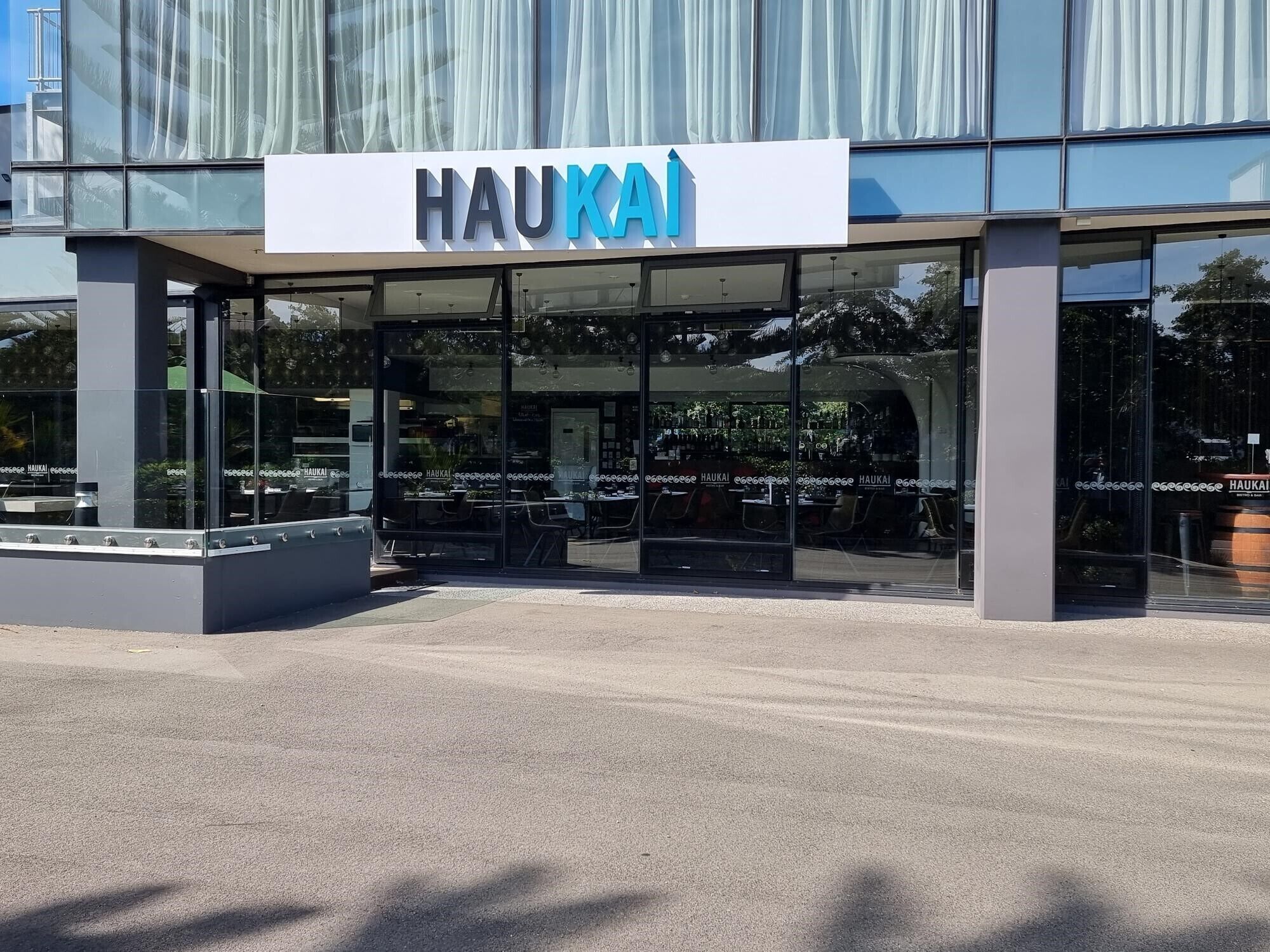 Un edificio moderno con fachada de vidrio y un letrero que dice 'HAUKAI'.