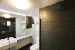 A modern bathroom with a large mirror, white sink, and a towel hanging on a rack.