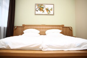 A neatly made bed with white linens and a wooden headboard.