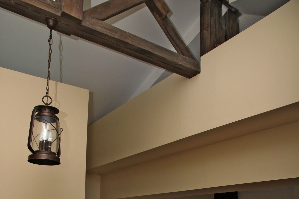 A bedroom with a wooden bed, a hanging lantern, and a window with a view of trees.