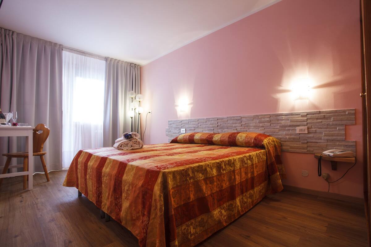 Une chambre d’hôtel avec un lit, un bureau, une chaise et un téléphone.