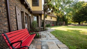 A red bench on a stone pathway leading to a building with a brick facade and a yellow exterior. - Rutgers University Inn and Conference Center (New Brunswick)
