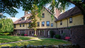 A two-story building with a brick facade, multiple windows, and a stone wall in the foreground. - Rutgers University Inn and Conference Center (New Brunswick)