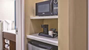 Una kitchenette compacta equipada con microondas, cafetera y lavavajillas.