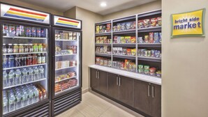Een supermarktinterieur met koelvitrines voor dranken en schappen vol snacks en ontbijtgranen.