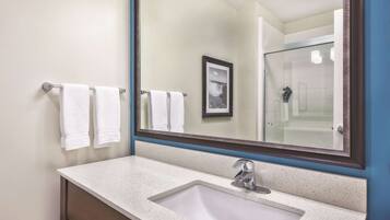 A bathroom with a white sink, a large mirror, and two towels hanging on a towel rack.
