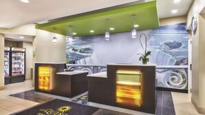 Een hotel receptie met een wanddecoratie van een waterval, een receptiebalie en een klok aan de muur.