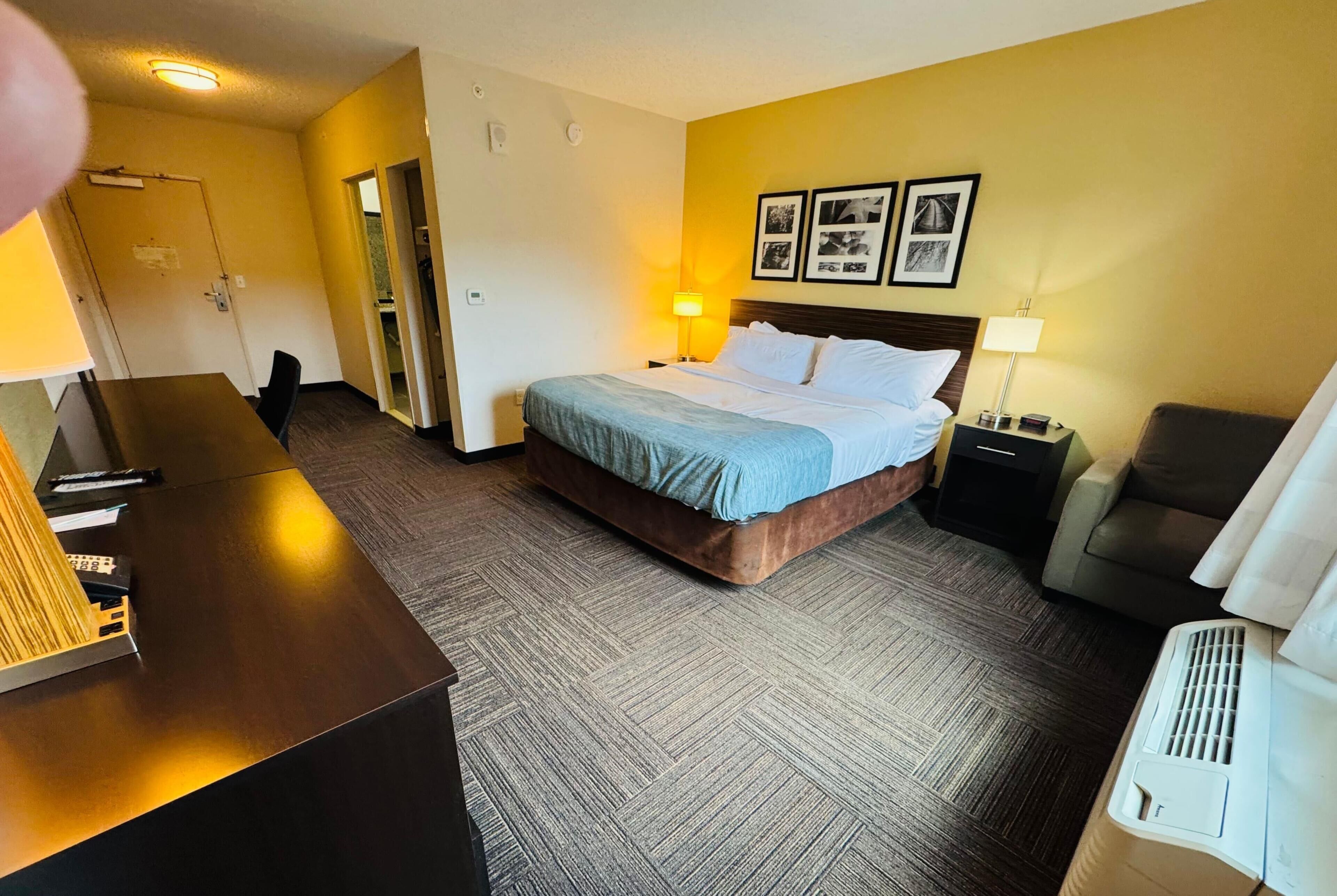 Ein Hotelzimmer mit Bett, Schreibtisch, Stuhl, Lampe und Heizung.