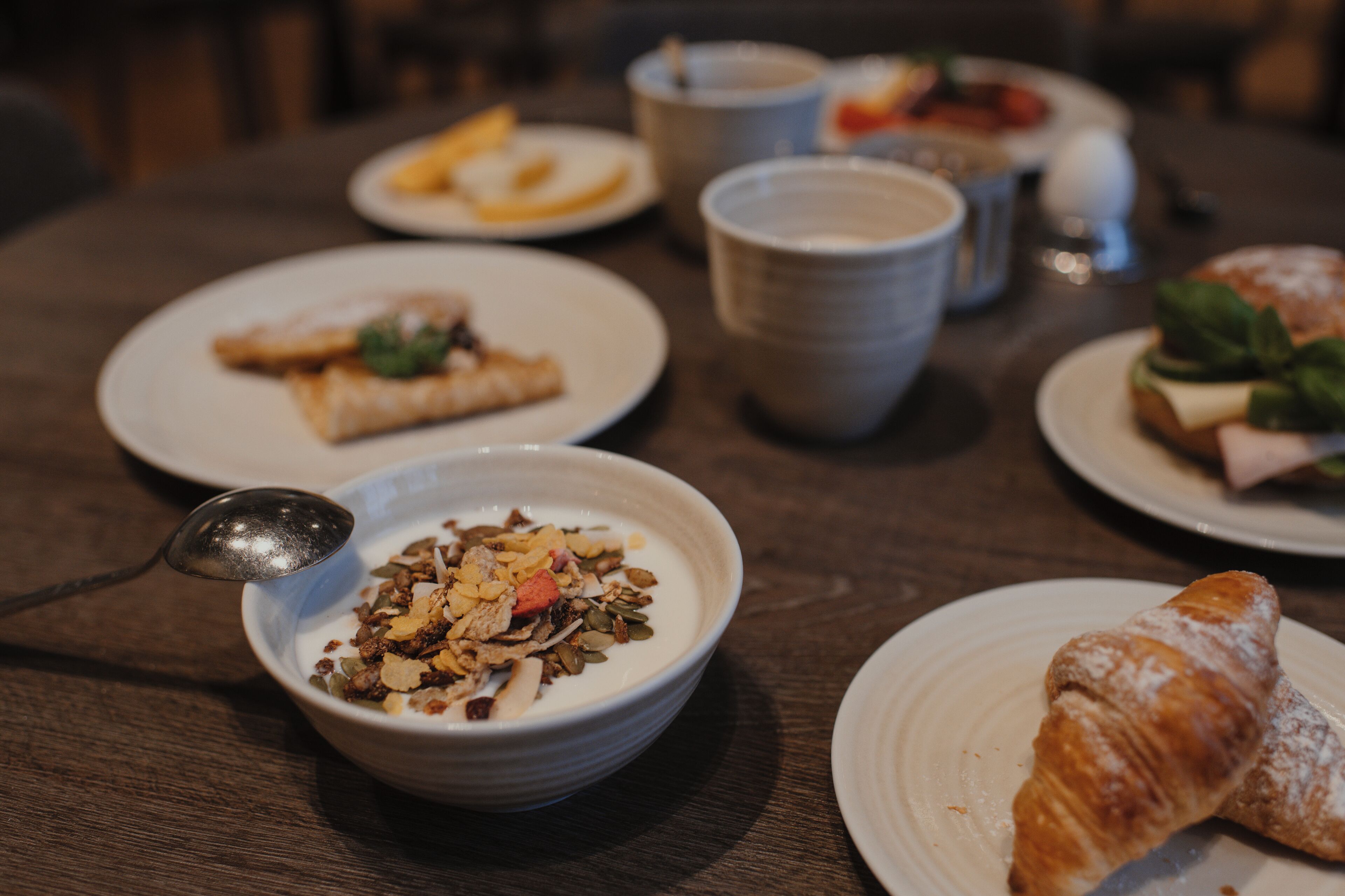 Una mesa con platos de comida, tazones y vasos.