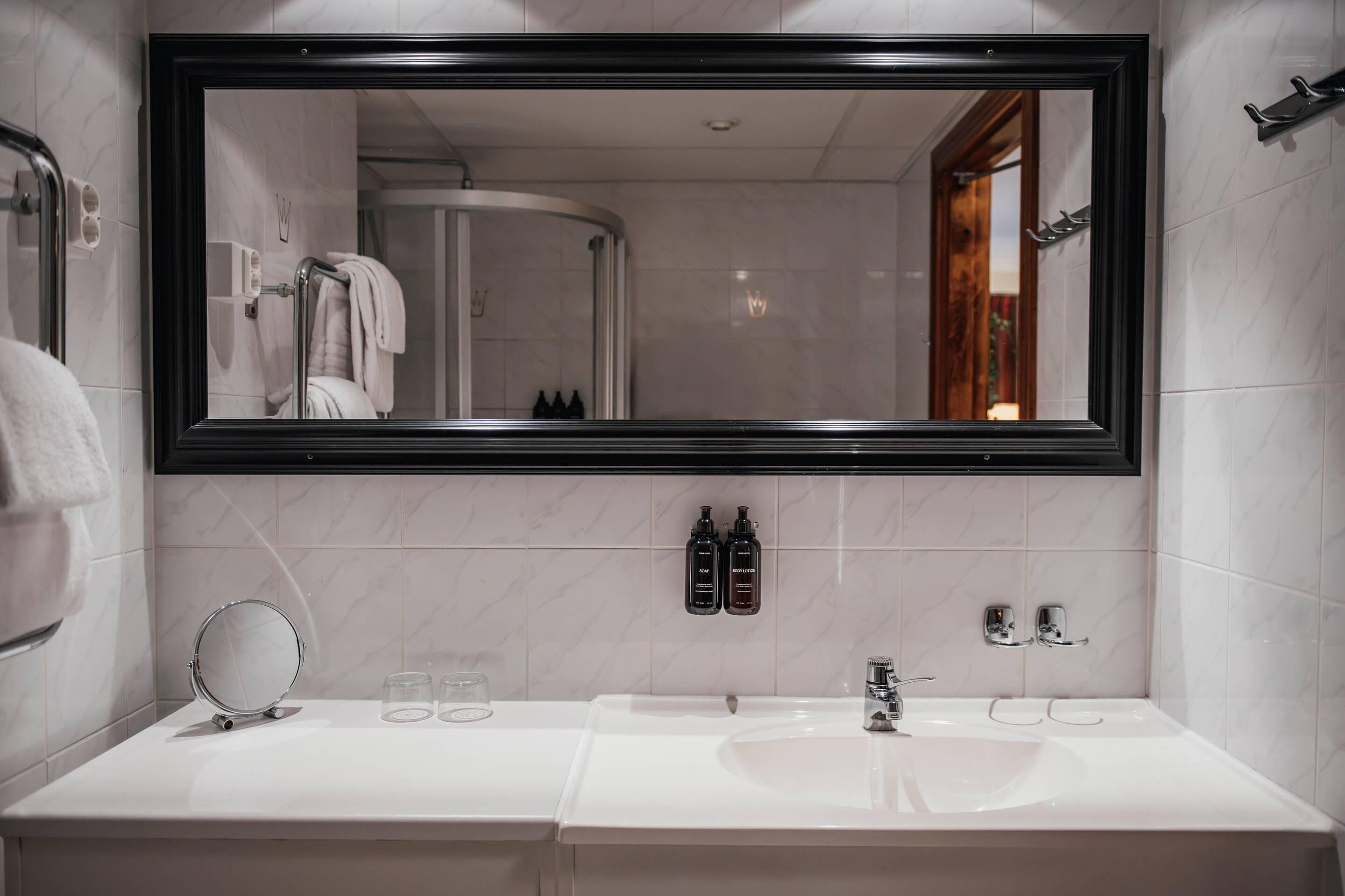 Un bagno con uno specchio grande, un lavandino e una zona doccia.