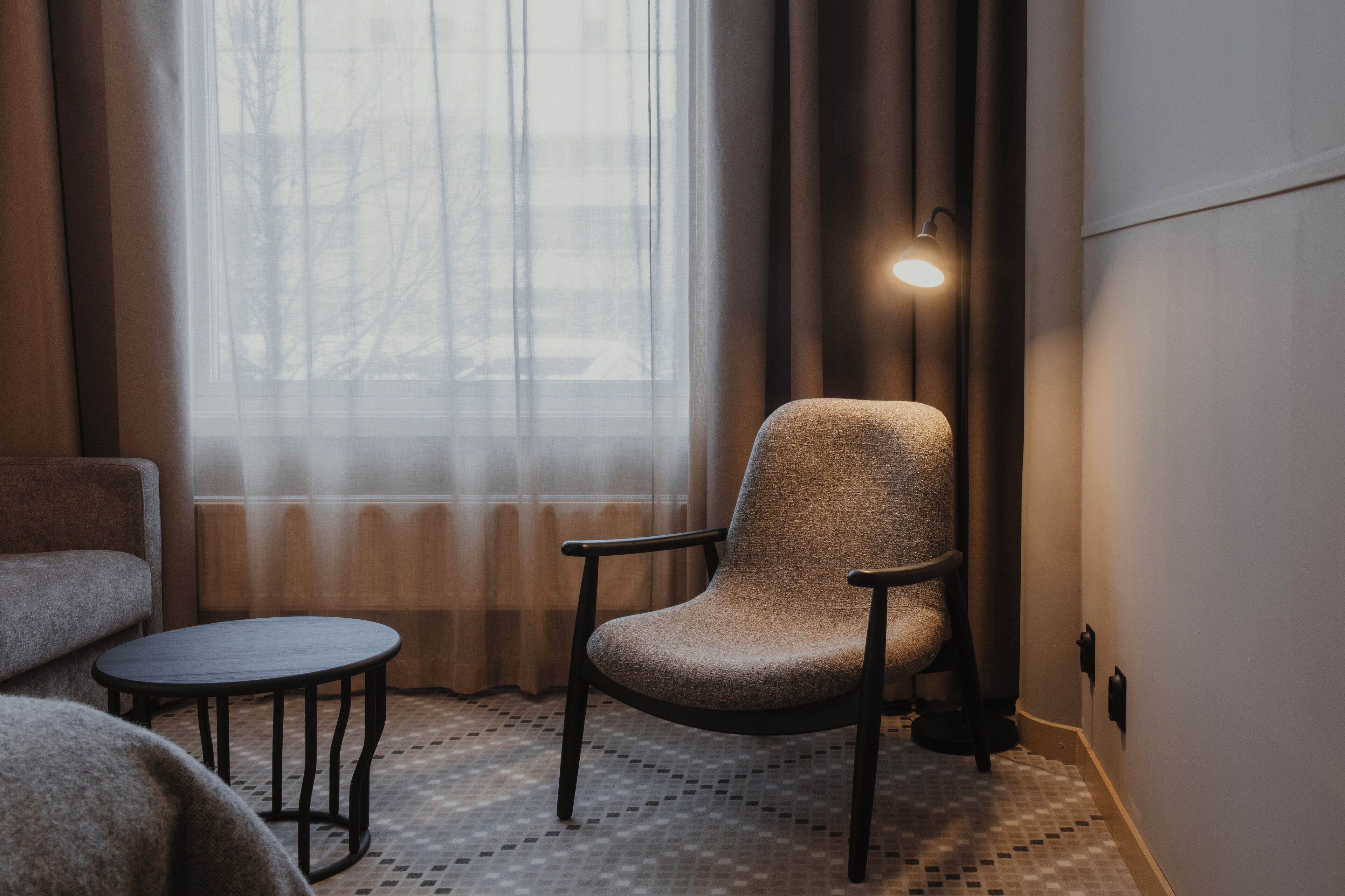 A room with a chair, a small round table, and a lamp.