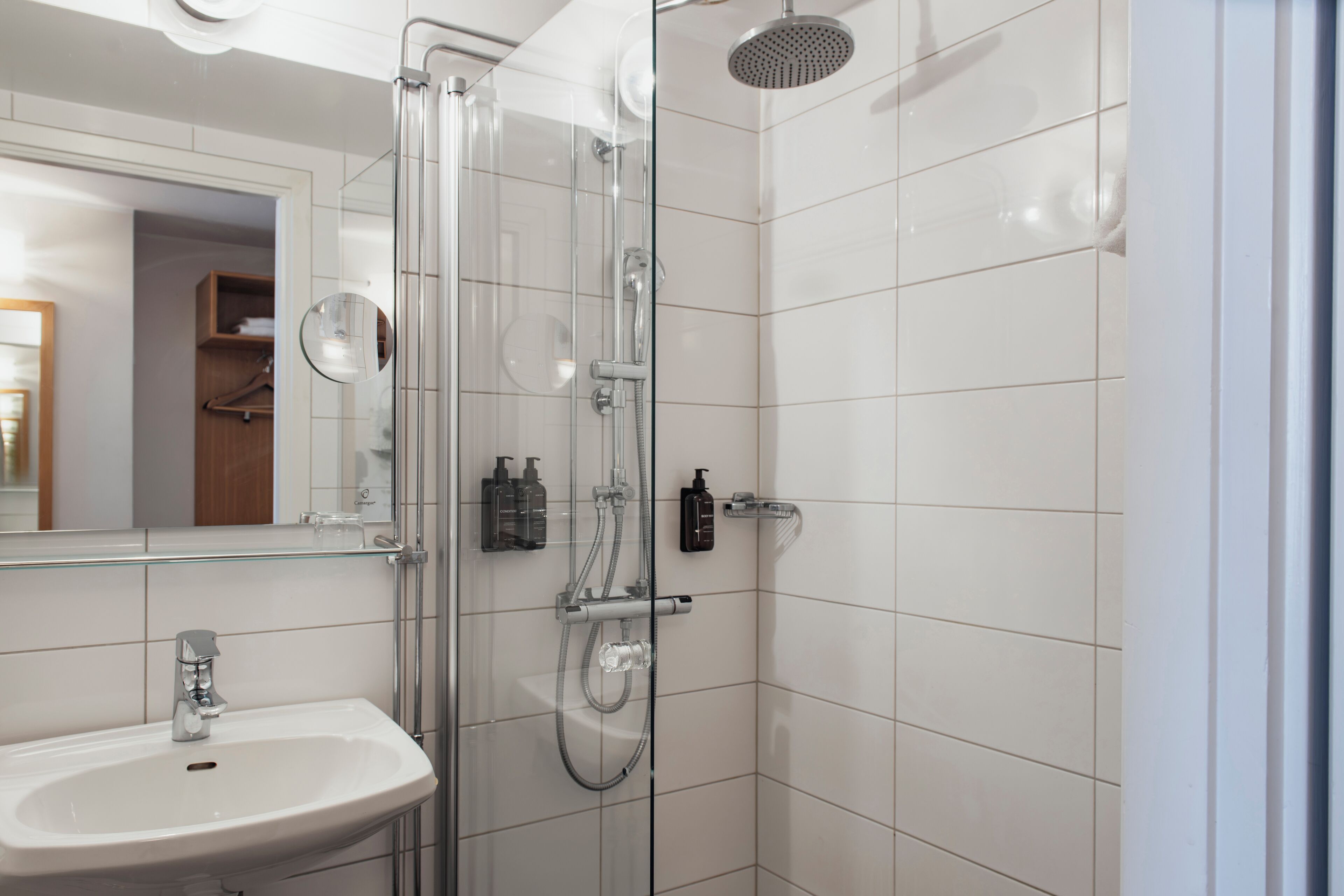A modern bathroom with a glass-enclosed shower, a sink, and a mirror.