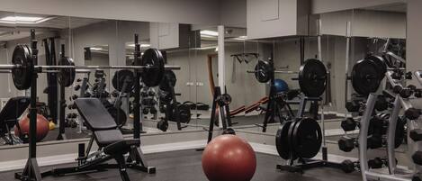 A gym with various exercise equipment, including weight machines, free weights, and exercise balls.