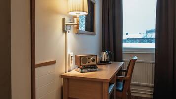 Habitación de hotel con un escritorio de madera, una radio, un hervidor y vistas a un paisaje nevado.