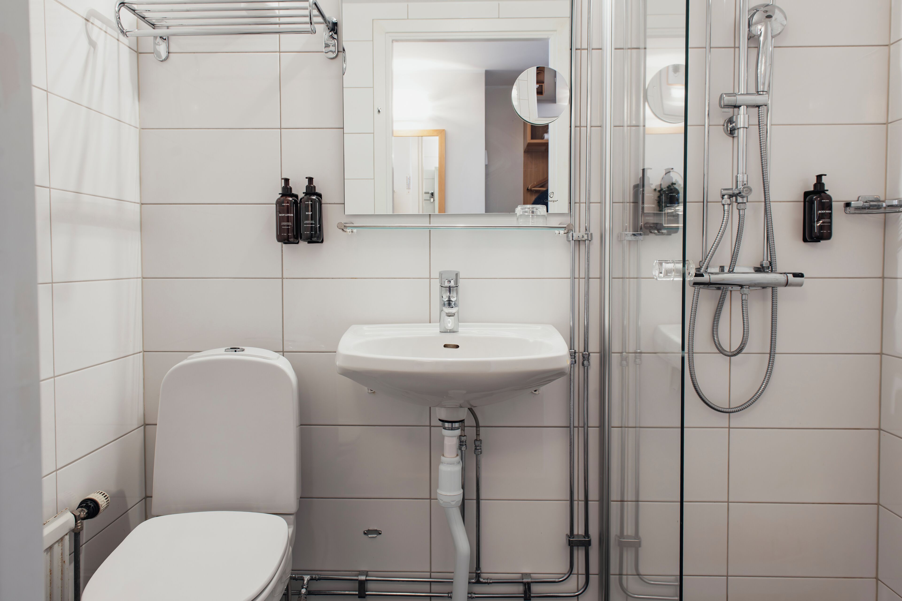 Une salle de bain moderne équipée de toilettes, d’un lavabo et d’une douche à parois de verre.