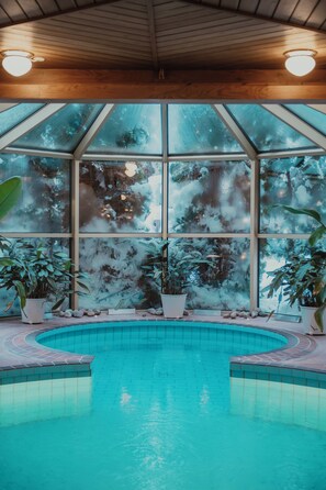 A swimming pool with a wooden ceiling and large windows. - Home Hotel Smedjan (Sandviken)