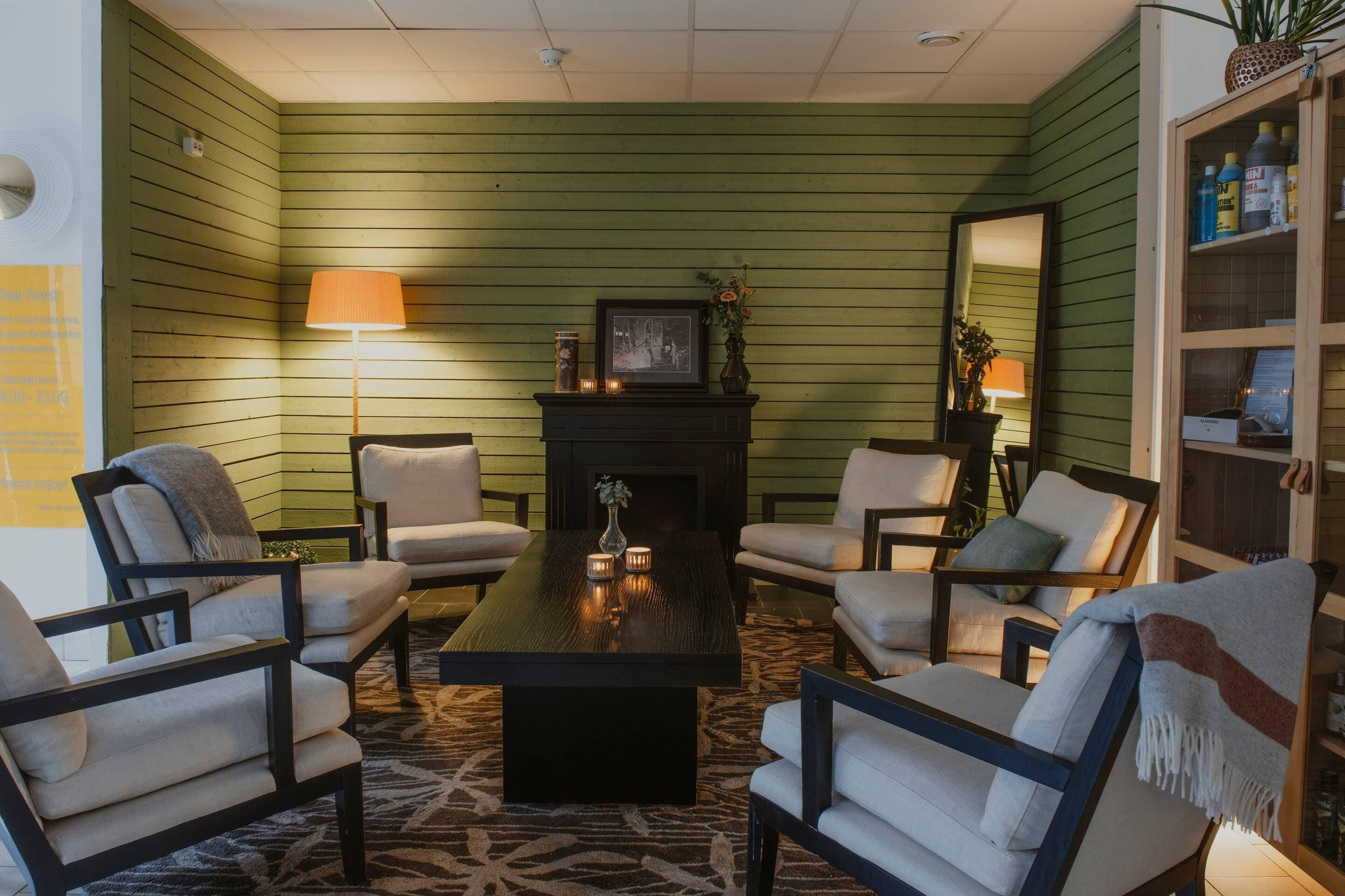 A room with green walls, a fireplace, a coffee table, and four armchairs.