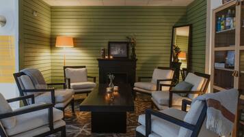 A room with green walls, a fireplace, a coffee table, and four armchairs.