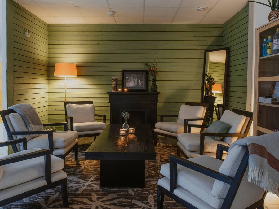 A room with green walls, a fireplace, a coffee table, and four armchairs.