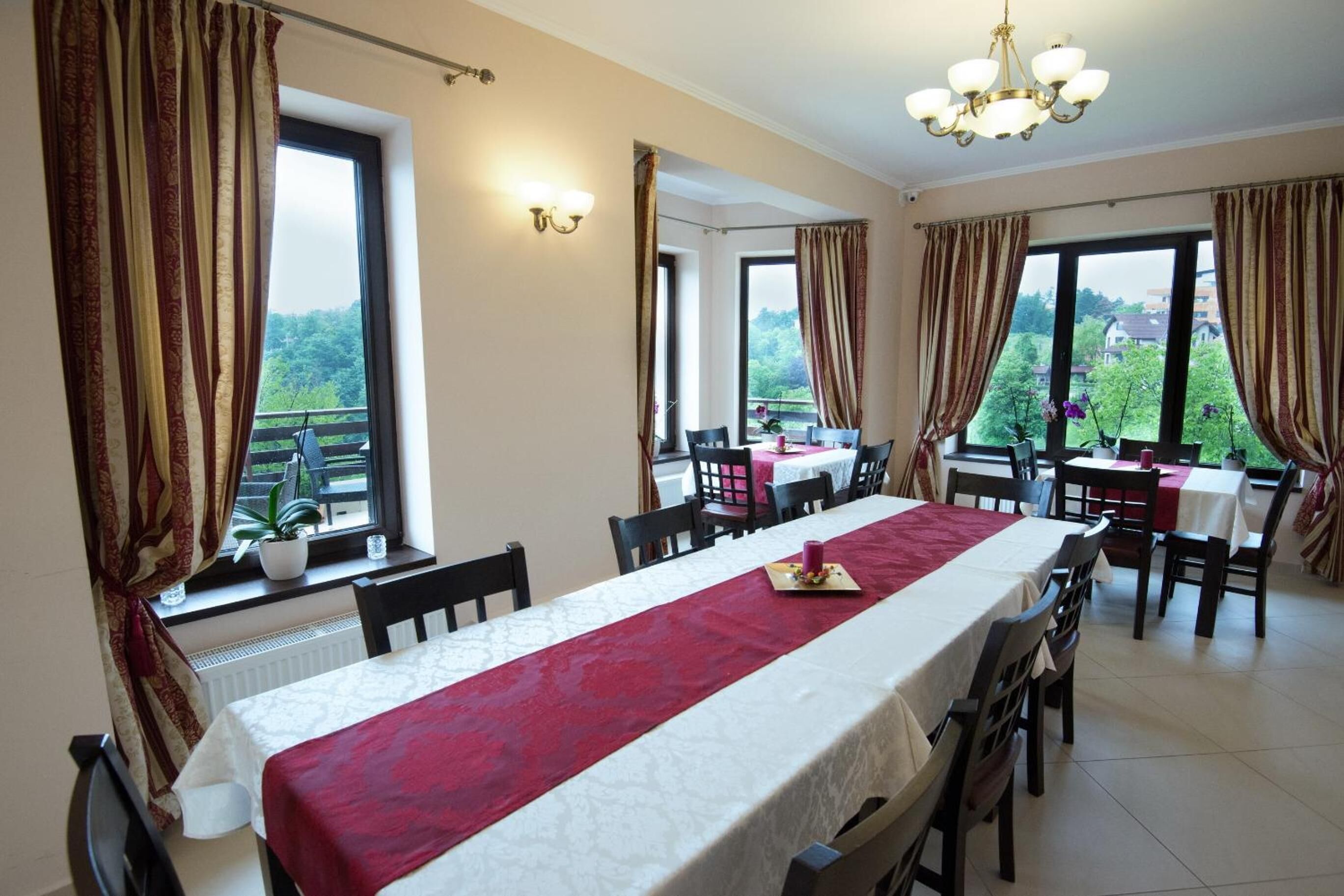 A dining area with a long table, chairs, and a view of greenery outside.